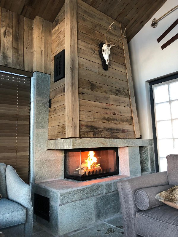 Side-glass fireplace with a stone base and a wooden covering - Carron-Lugon